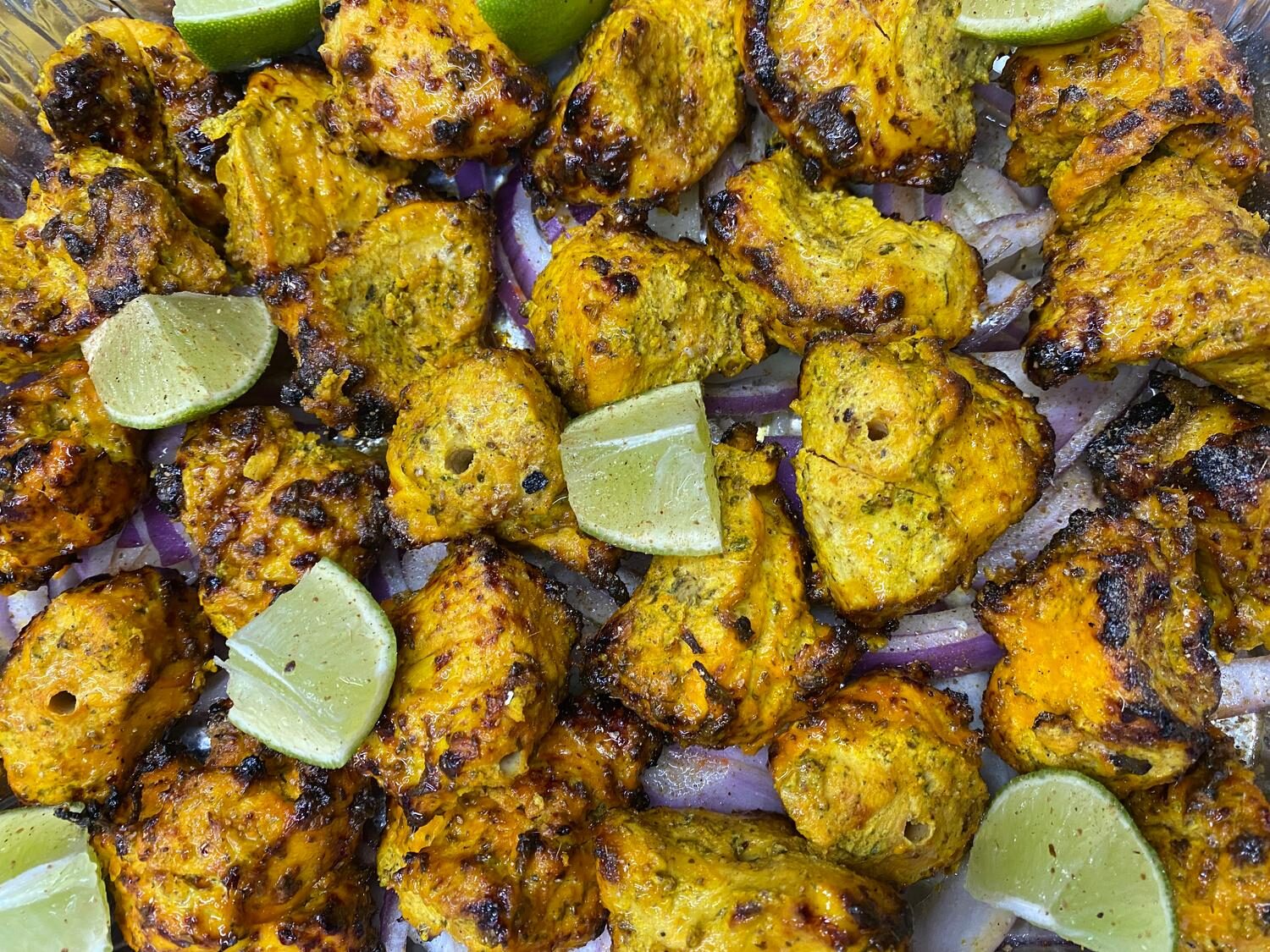 Golden turmeric-marinated chicken malai tikka with red onions and lime