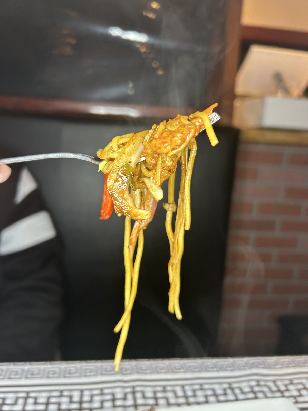 A steaming forkful of chicken hakka noodles with peppers