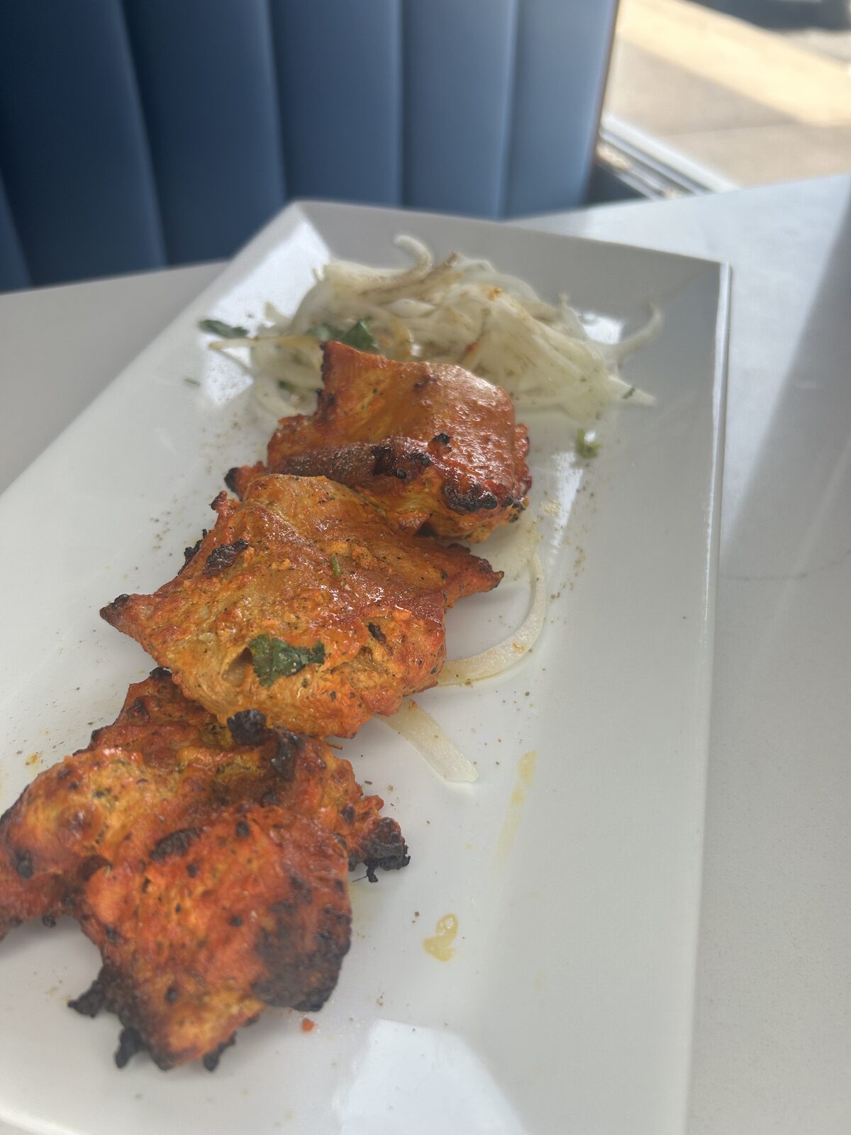 Chicken tikka skewers fresh from the tandoor with onion salad