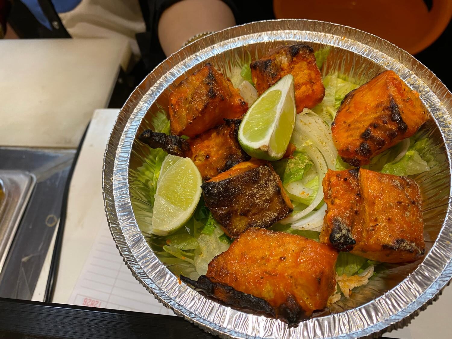 Tandoori salmon tikka with charred edges served over crisp lettuce and lime